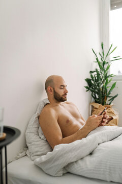 Young handsome man using his mobile phone in the bed