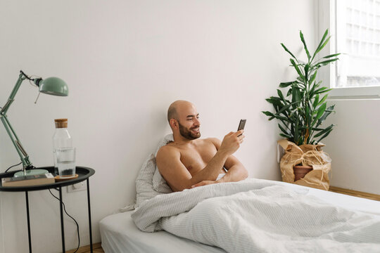 Young handsome man using his mobile phone in the bed