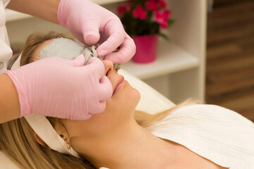 young woman is put on an alginate mask of gray color. Beauty treatment