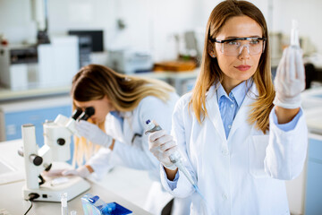 Female doctor wearing protective  face mask in lab holding flask with liquid sample