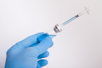  The doctor is holding a syringe and  medicine bottle in his hand.