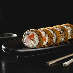 Hot fried sushi roll with salmon. Sushi menu. Japanese food. Hot fried sushi roll on black background