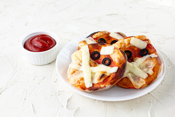 Mini pizza as mummy for kids with cheese, olives and ketchup. Funny crazy Halloween food for children