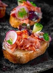 Tasty bruschetta with salmon, cucumber and cream cheese in plate