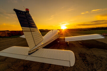 Quadruple aircraft parked at a private airfield. Rear view of a plane with a propeller on a sunset...