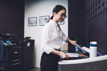 Female secretary cutting paper in office