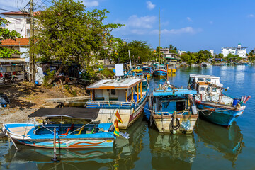 Fototapeta na wymiar Brightly coloured fishing vessels line the shore of the lagoon in Negombo, Sri Lanka