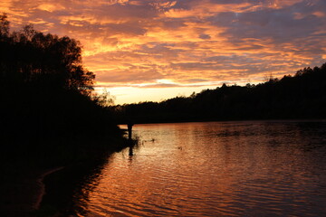 Fototapeta premium Beautiful blazing sunset landscape above river and orange sky in evening