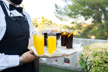 waiter carrying tray with glasses with soft drinks