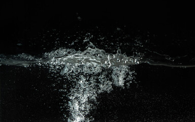 Naklejka na ściany i meble Water splashing as it's poured into aquarium tank, black background