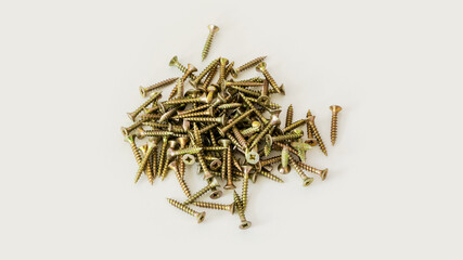 heap of golden yellow metal screws isolated on white background