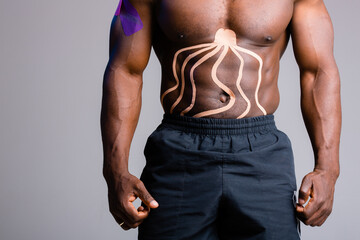Fototapeta na wymiar muscular African American torso. Kinesitherapy tape glued to the abdominal muscles