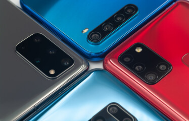 Four bright multicolored modern smartphones with different foto camera modules close-up. Selective focus.