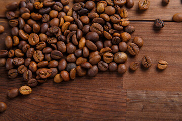 A scattering of coffee beans on a wooden table.