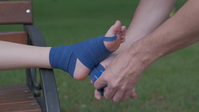 Wrap The Leg With An Elastic Bandage. The Ankle Of A Teenager Is Wrapped In An Elastic Bandage In Nature.