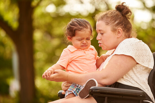 Disabled mother holding crying child on her lap.