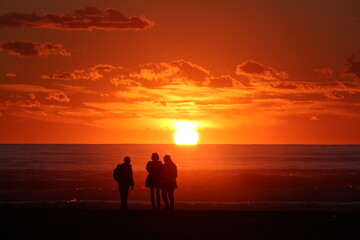 Fototapeta na wymiar persone che ammirano il tramonto in riva al mare