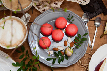 Five macaroons on a grey plate with almonds, pears and coffee