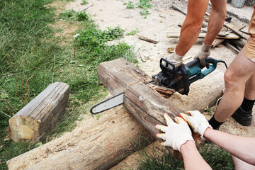 A man saws wood with a saw outside on a summer day. Work concept.