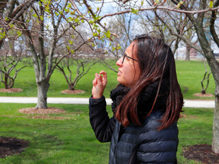 woman in the park wearing a black jacket and black glasses in a sunny spring day