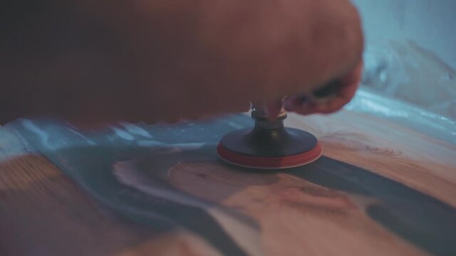 Man polishing wood. Epoxy table making process. Hipster handmade furniture design