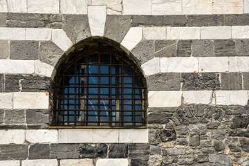 Obraz premium Close-up of an arched window of the Church of St Peter with horizontal black and white stripes of marble and stone, Porto Venere, La Spezia, Liguria, Italy