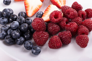 Close-up of three small bowls overflowing with summer berries, strawberries, raspberries, blueberries