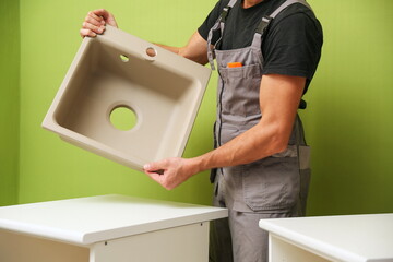 refurbishment in the apartment. hands of worker installs kitchen sink