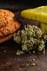 biscuits with marijuana and cannabis butter and bud on rust metal background close-up. Healthy medical food with cannabis. the buds are inaccurately scattered. rustic. Vertical.