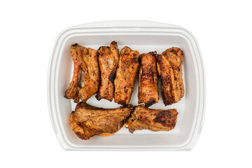 Grilled pork ribs in a white box, top view, isolated