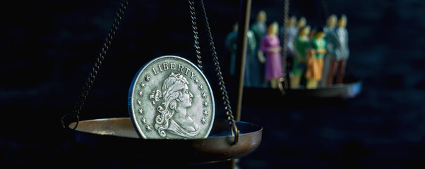 Conceptual image of price of financial freedom. Weight between money and people. Selective focus on coin.
