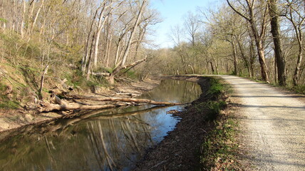 A bare gravel path winds its way through the woods along the Potomac River and the C&O Canal Towpath in rural Maryland.