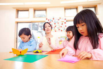 折り紙を折る幼稚園児と幼稚園教諭