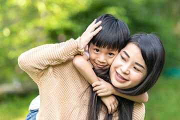 Portrait beautiful mother and child happily hugged in park. Asian family mom and child are hugging and looking at the camera, cute and warm.