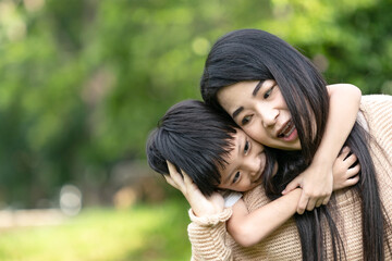 Portrait beautiful mother and child happily hugged in park. Asian family mom and child are hugging and looking at the camera, cute and warm.