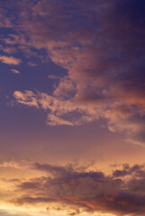 Vertical photo. Magical sunset. Cloudscape. View of the dramatic sky and clouds during twilight with beautiful dusk colors, purple, orange and magenta.