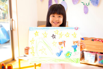 絵を持って微笑む幼稚園女児