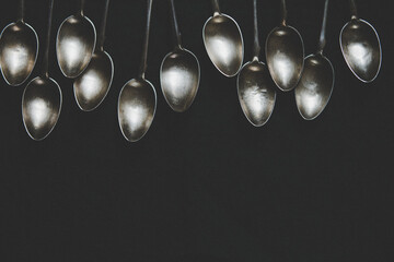 A row of silver tea spoons laying on canvas cloth, background