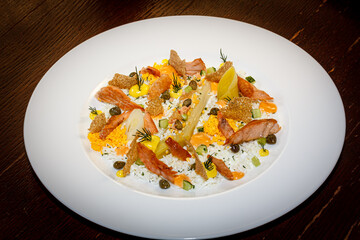 Rice with salmon slices and vegetables is on a plate