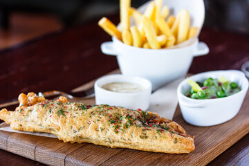 Fish & Chips . Deep-fried fish with potatoes and a sauce of green peas and tar lies on the Board.