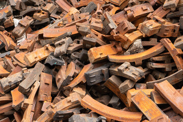 Pile of rusty steel brake pad of locomotive in old abandoned yard of train part manufacturing factory, vintage railway industry