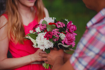 Beautiful bouquet in the hands of a young couple in love
