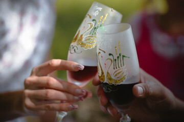 Hands of a man and a woman close-up holding glasses of win