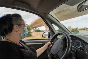 Obraz na płótnie Canvas Woman driving a vehicle with a protective mask.
