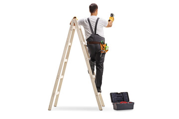 Rear view shot of a repairman on a ladder drilling with a machine into a wall - obrazy, fototapety, plakaty