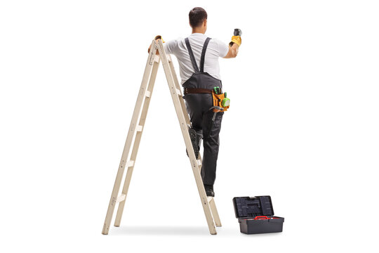 Rear view shot of a repairman on a ladder drilling with a machine into a wall