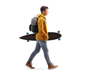 Male teenage student in a yellow hoodie walking and holding a longboard