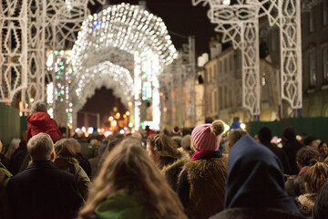 A crowd gathers in George Street, Edinburgh's City Center, Scotland, UK, watching the light show and Christmas carols taking place during the events held in the city during the festive period.