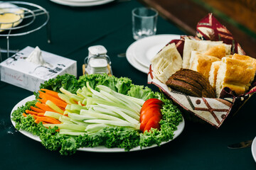 Fresh green salad with cucumber, tomato and carrots and bread behind