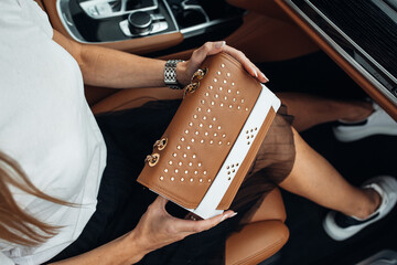 Women is holding handbag at the luxury car. Lady with bag inside modern and expensive luxury car 